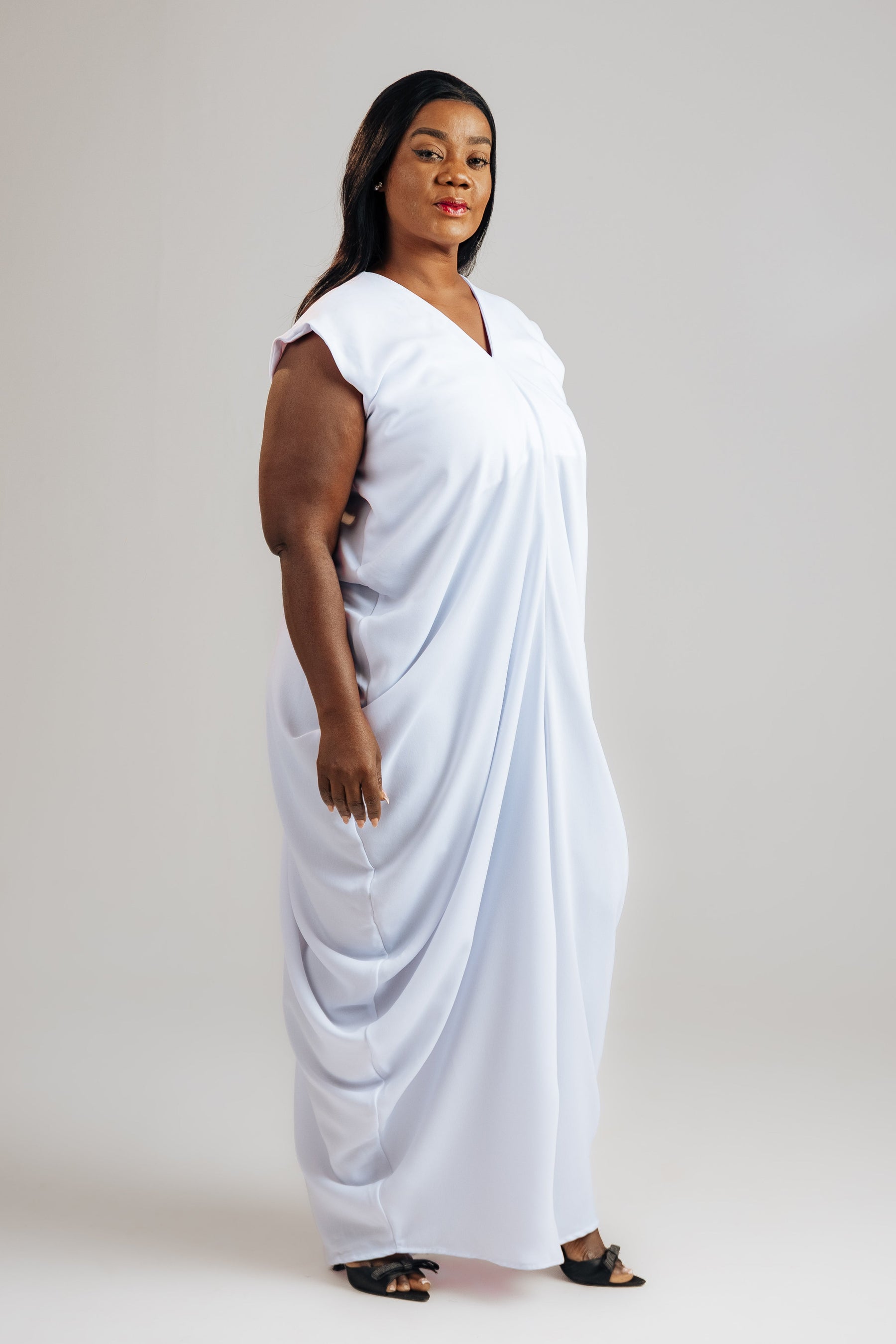 Woman wearing a white draped garment against a plain background