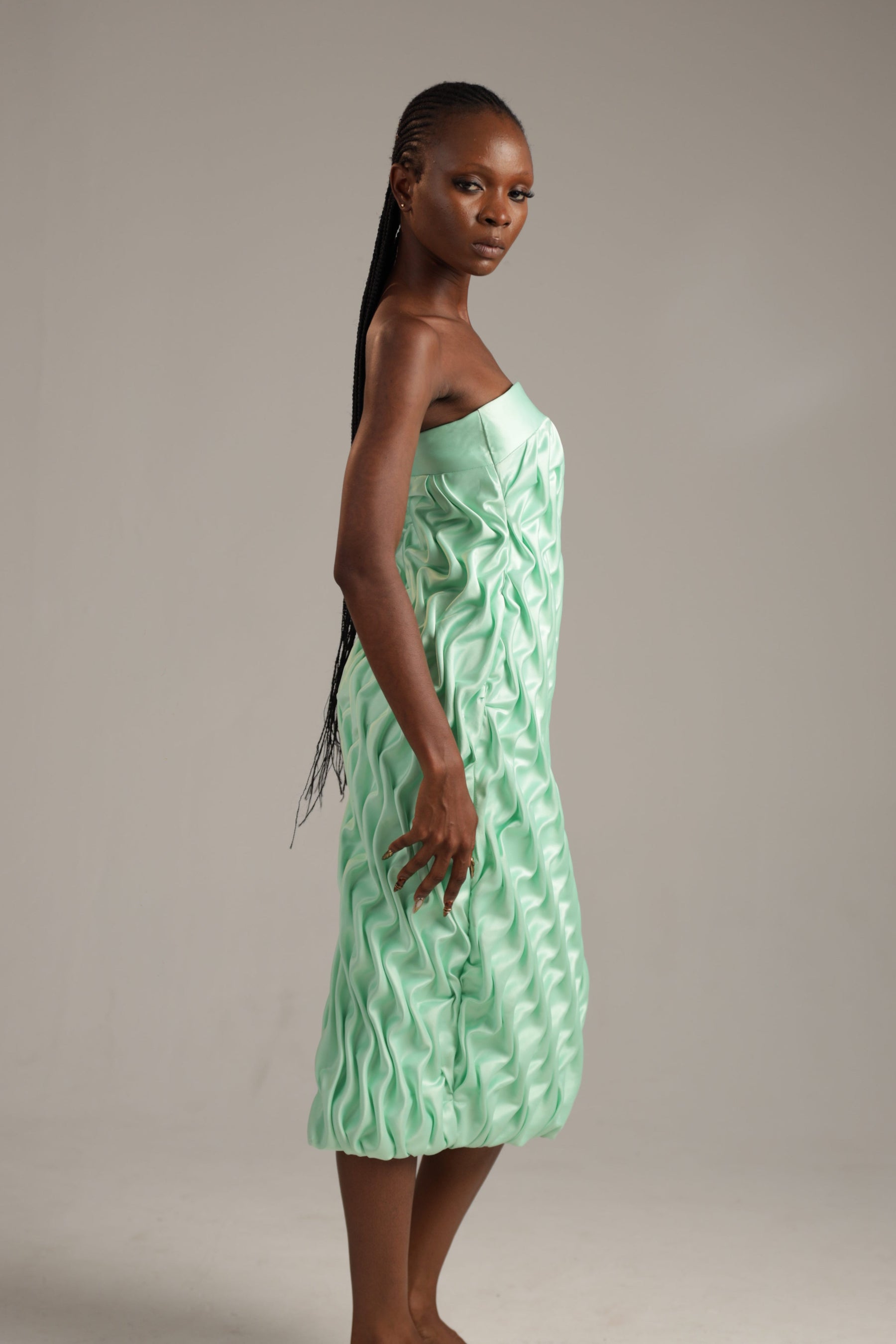 Woman wearing a light green strapless dress against a plain background