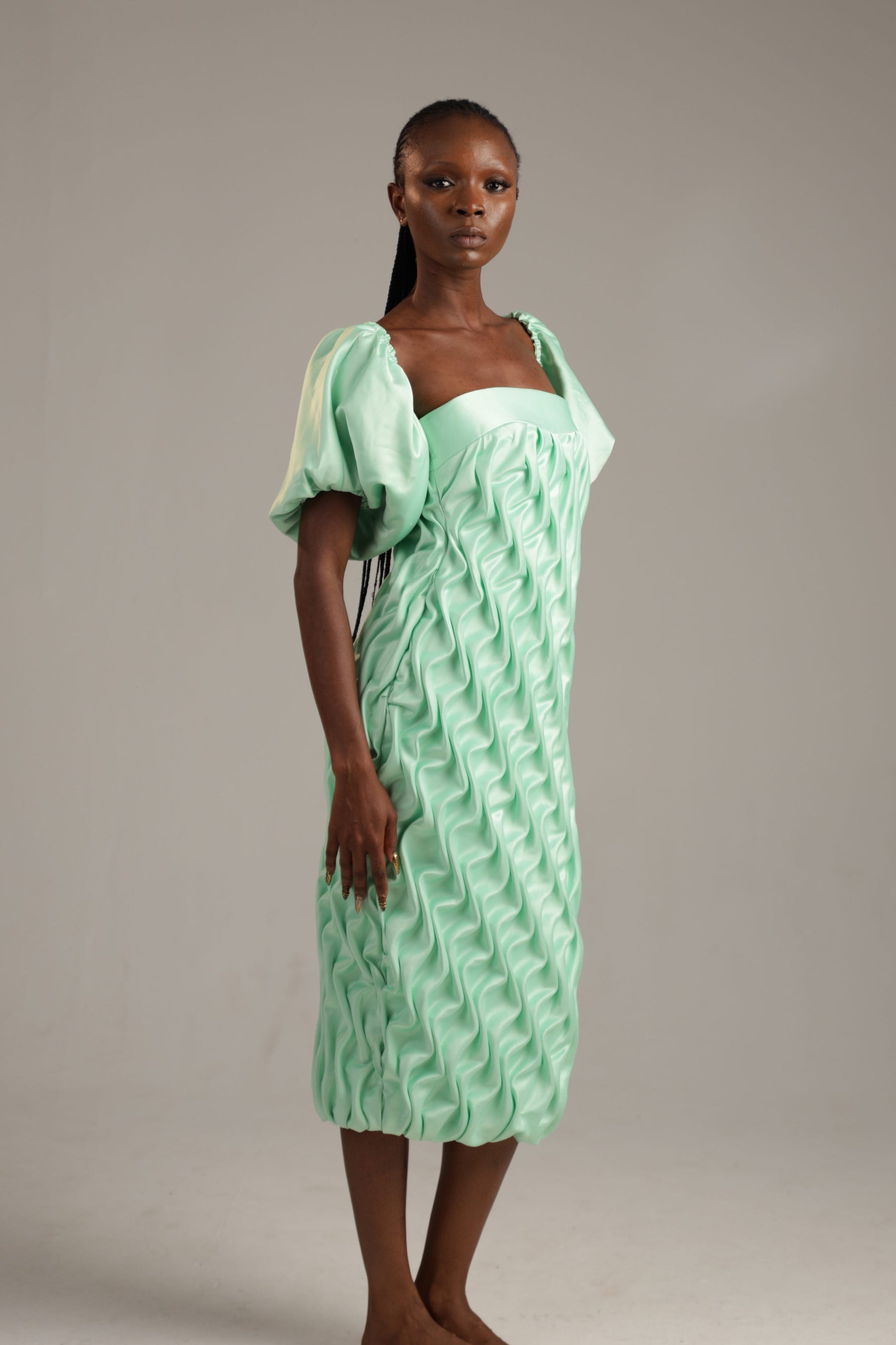 Woman wearing a green dress with a textured pattern on a plain background