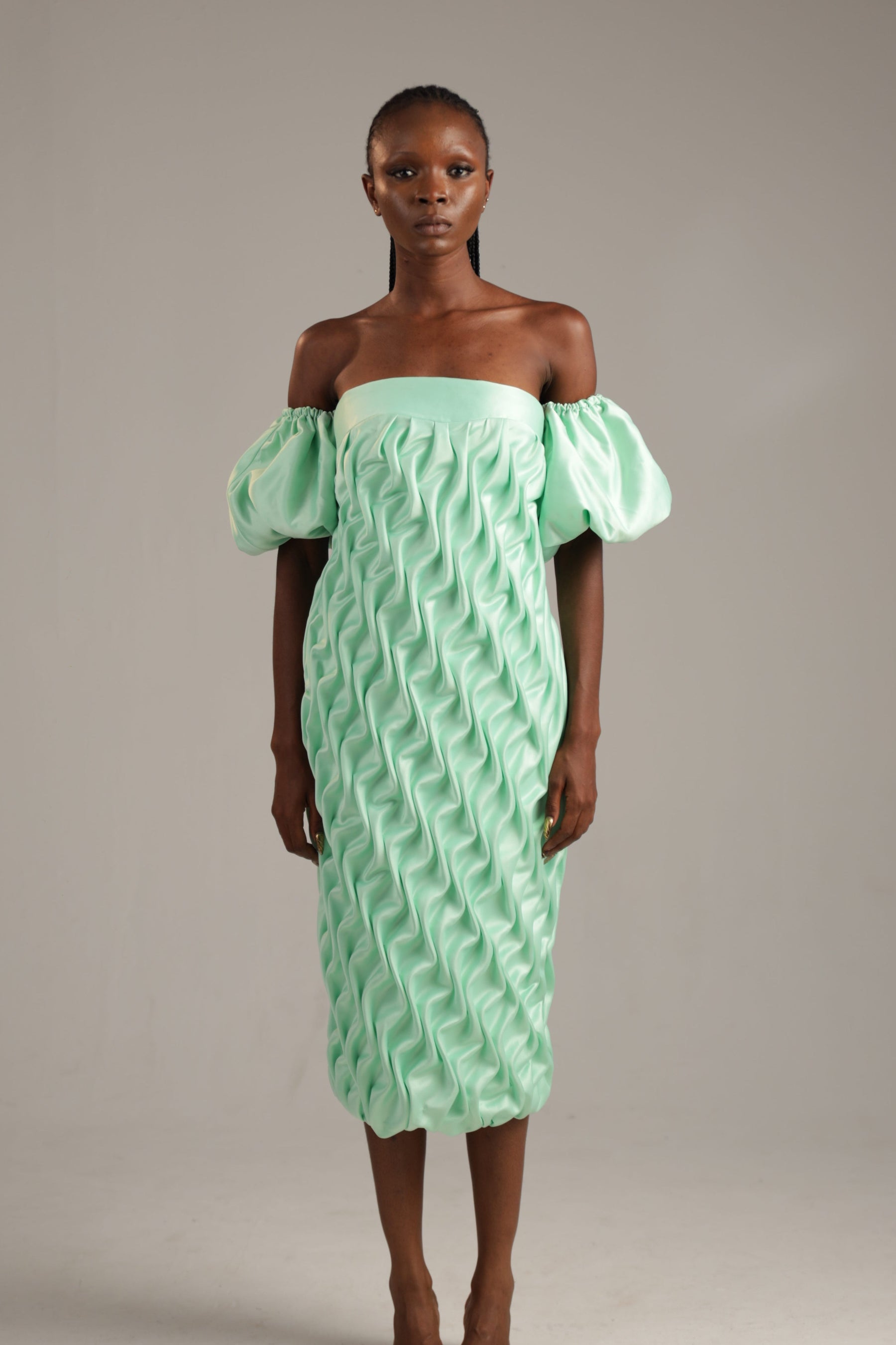 Woman wearing a light green off-shoulder dress against a plain background