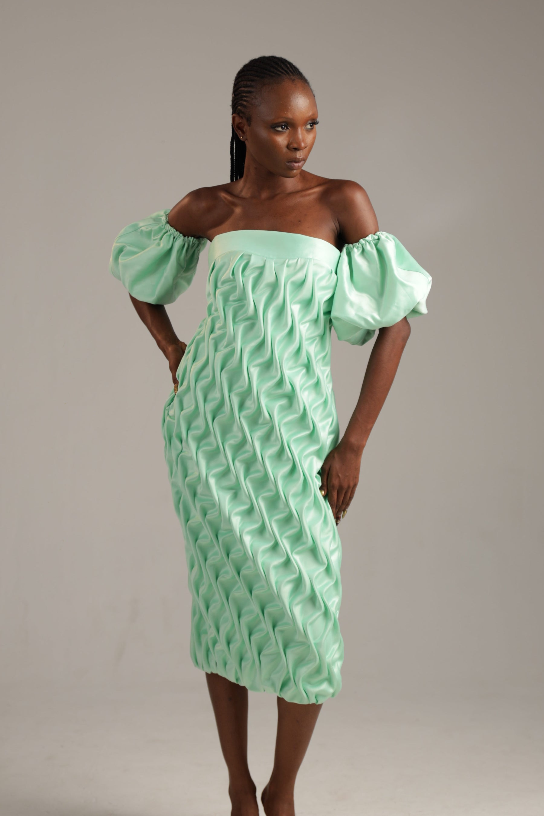 Woman wearing a light green dress with puffed sleeves against a neutral background