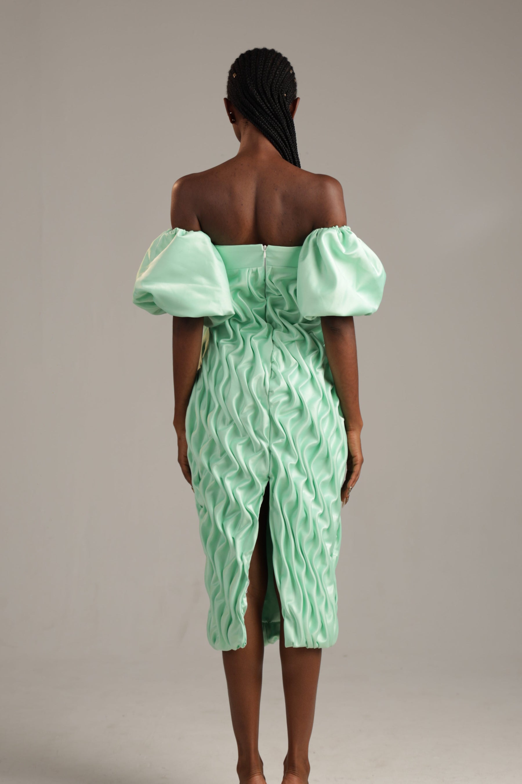 Woman wearing a light green off-shoulder dress against a plain background