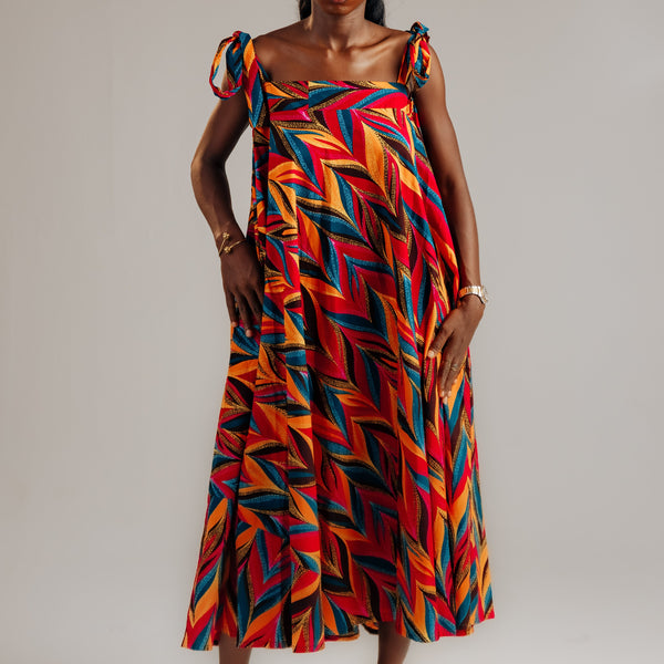 Woman wearing a colorful zigzag patterned dress on a plain background