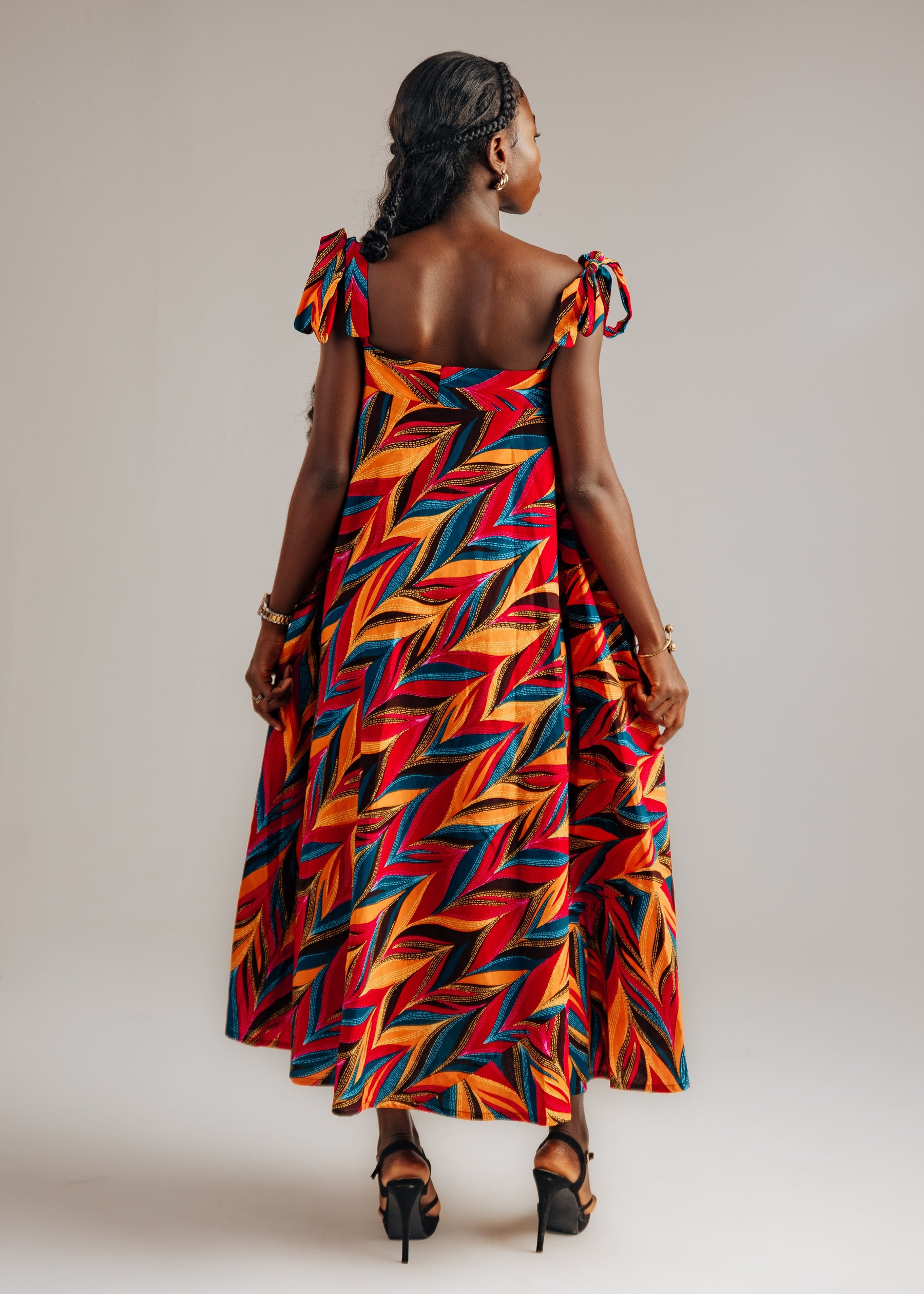 Woman wearing a colorful zigzag patterned dress on a plain background