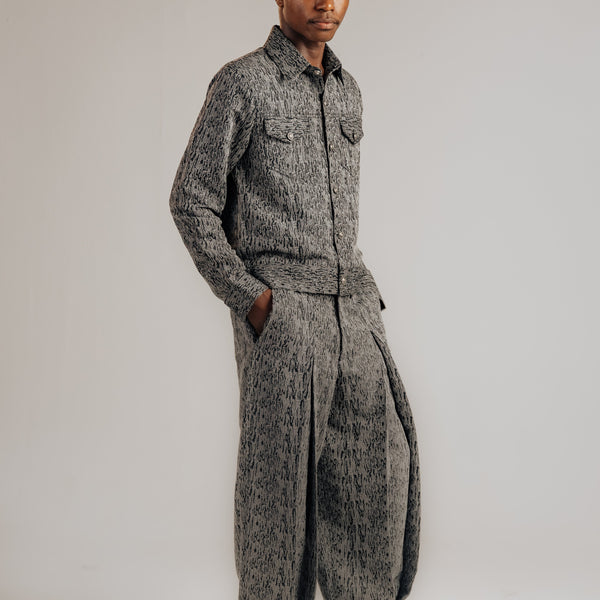 Person wearing a gray patterned outfit on a plain background