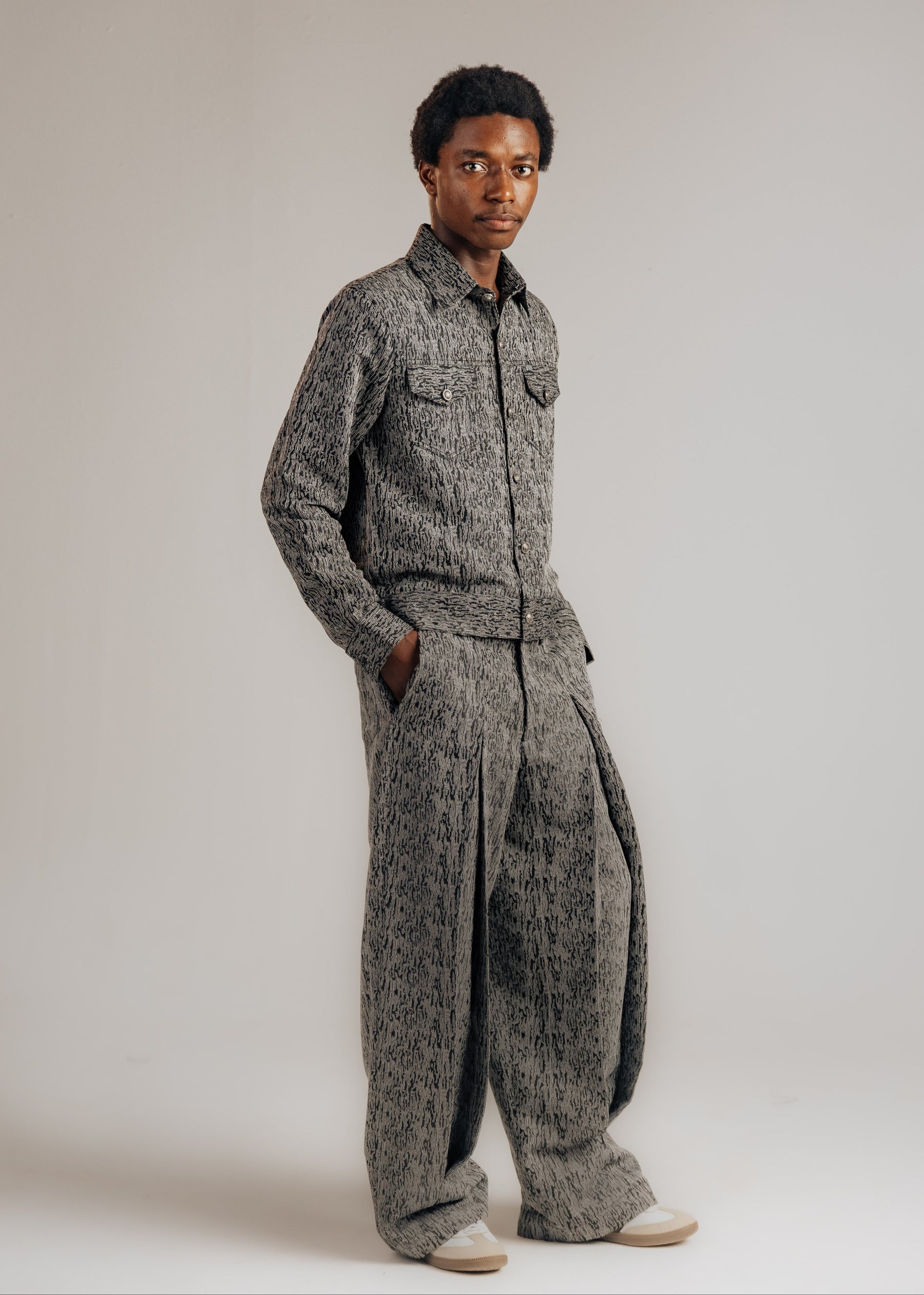 Person wearing a gray patterned outfit on a plain background