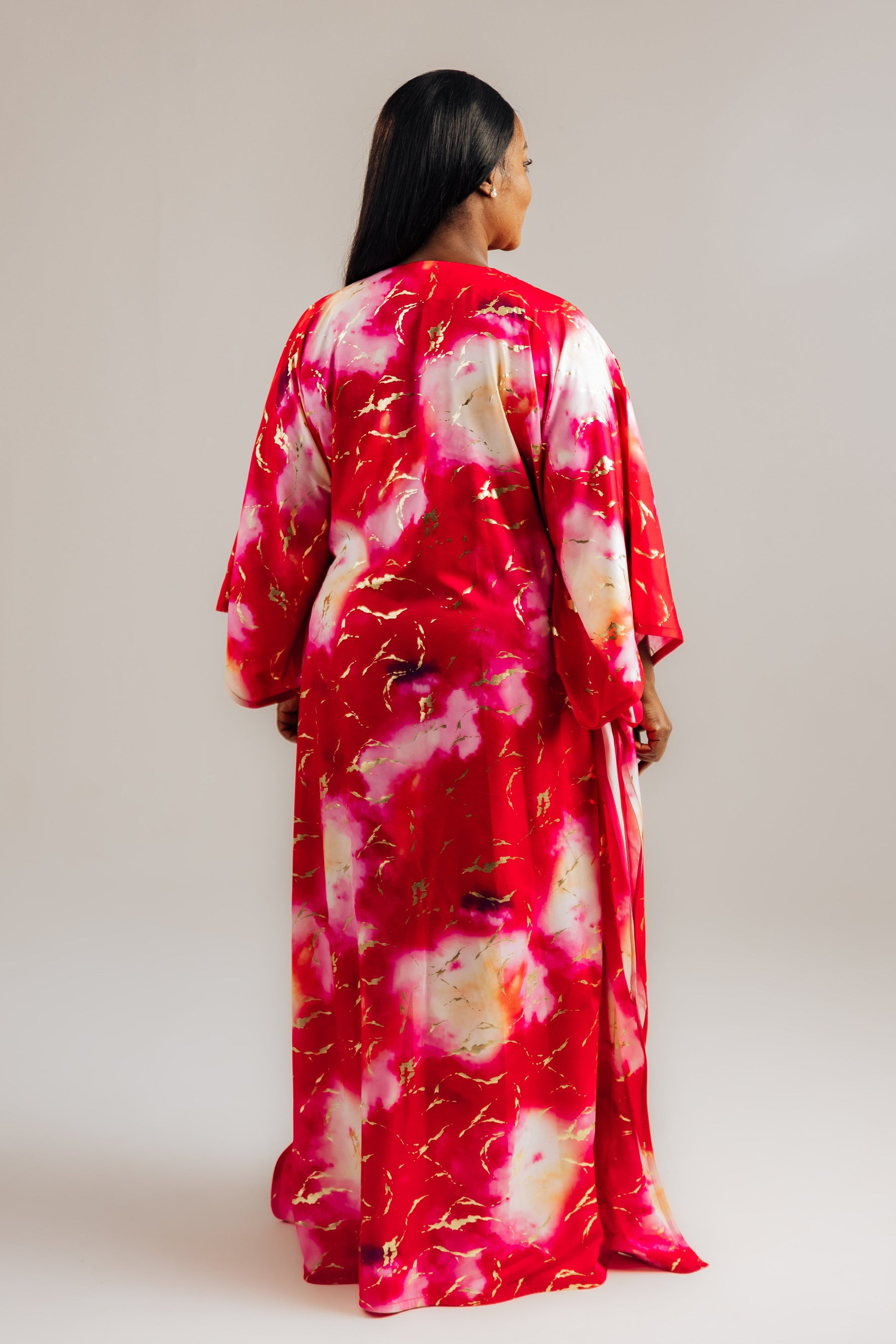 Woman wearing a red and white floral kimono-style dress against a plain background