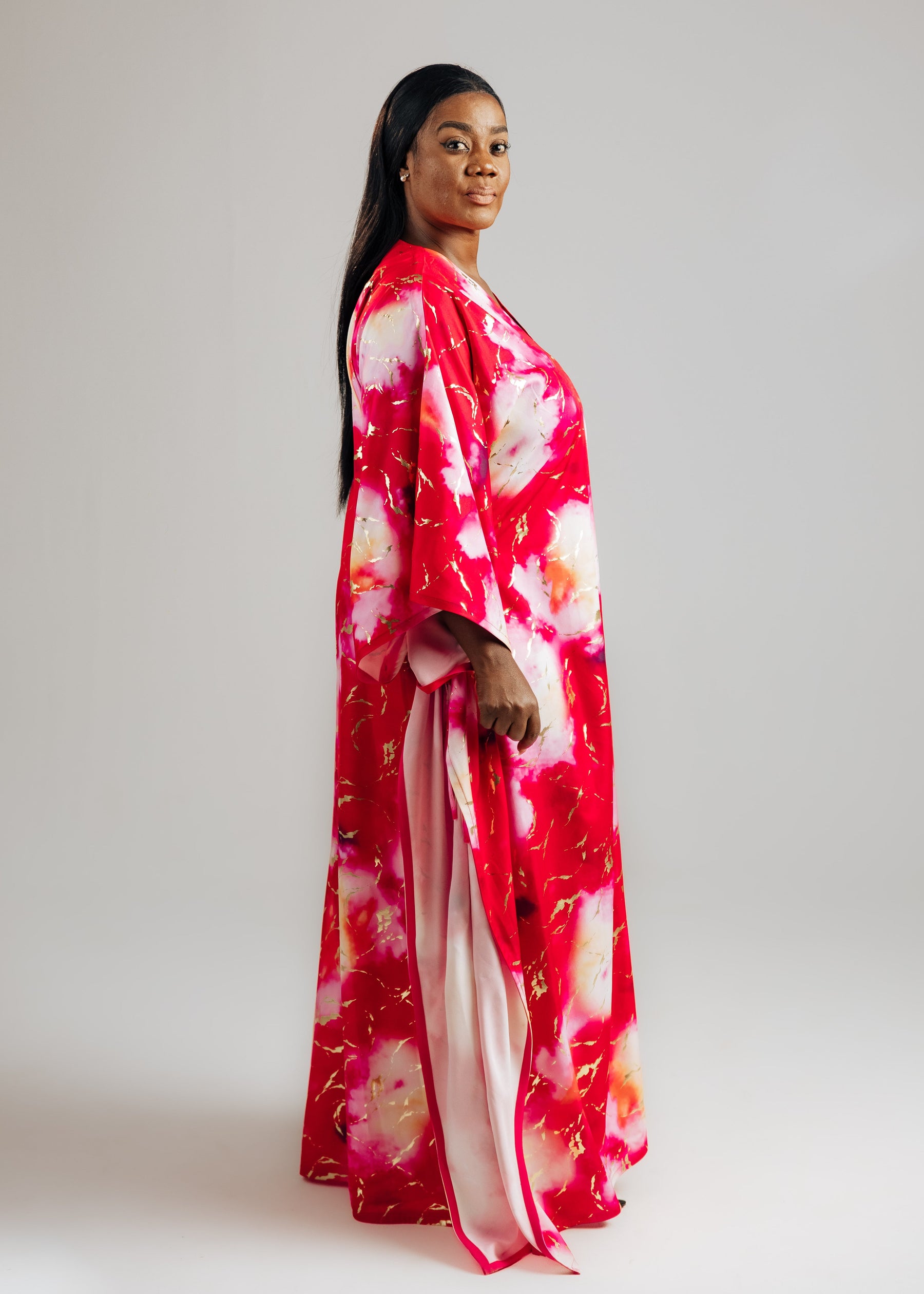 Woman wearing a red and white tie-dye dress against a plain background