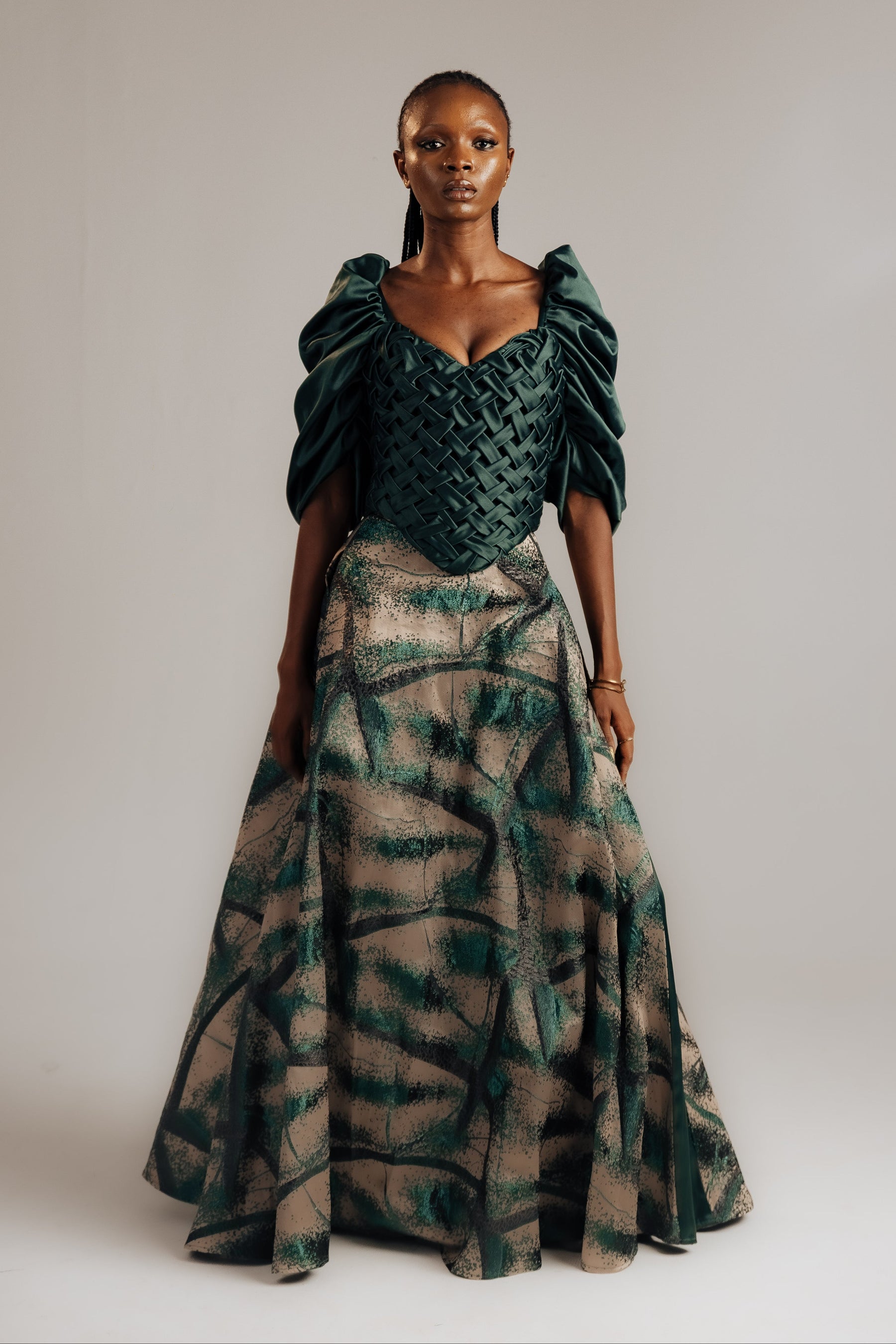 Woman wearing a green and brown patterned dress against a plain background