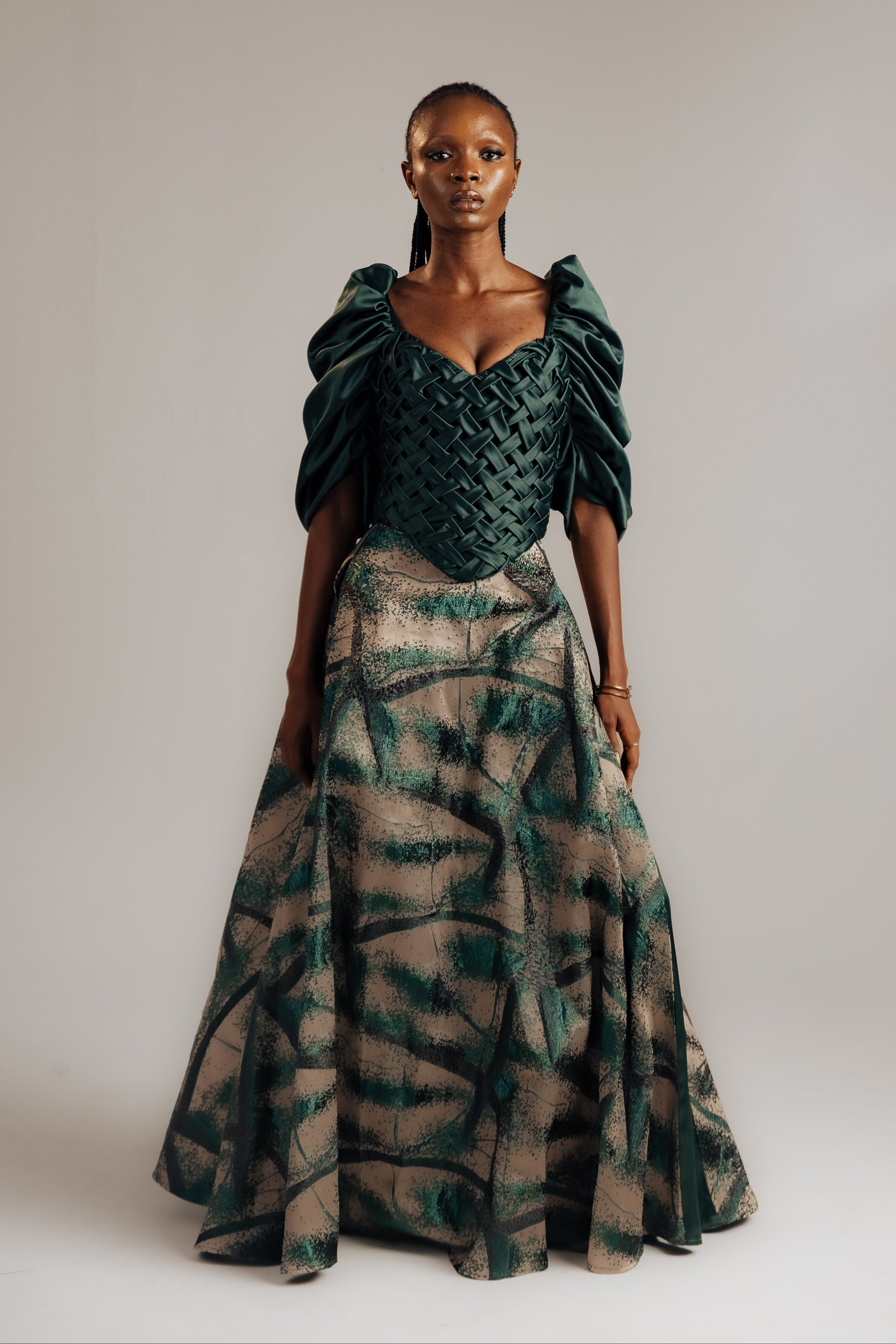 Woman wearing a green and brown patterned dress against a plain background