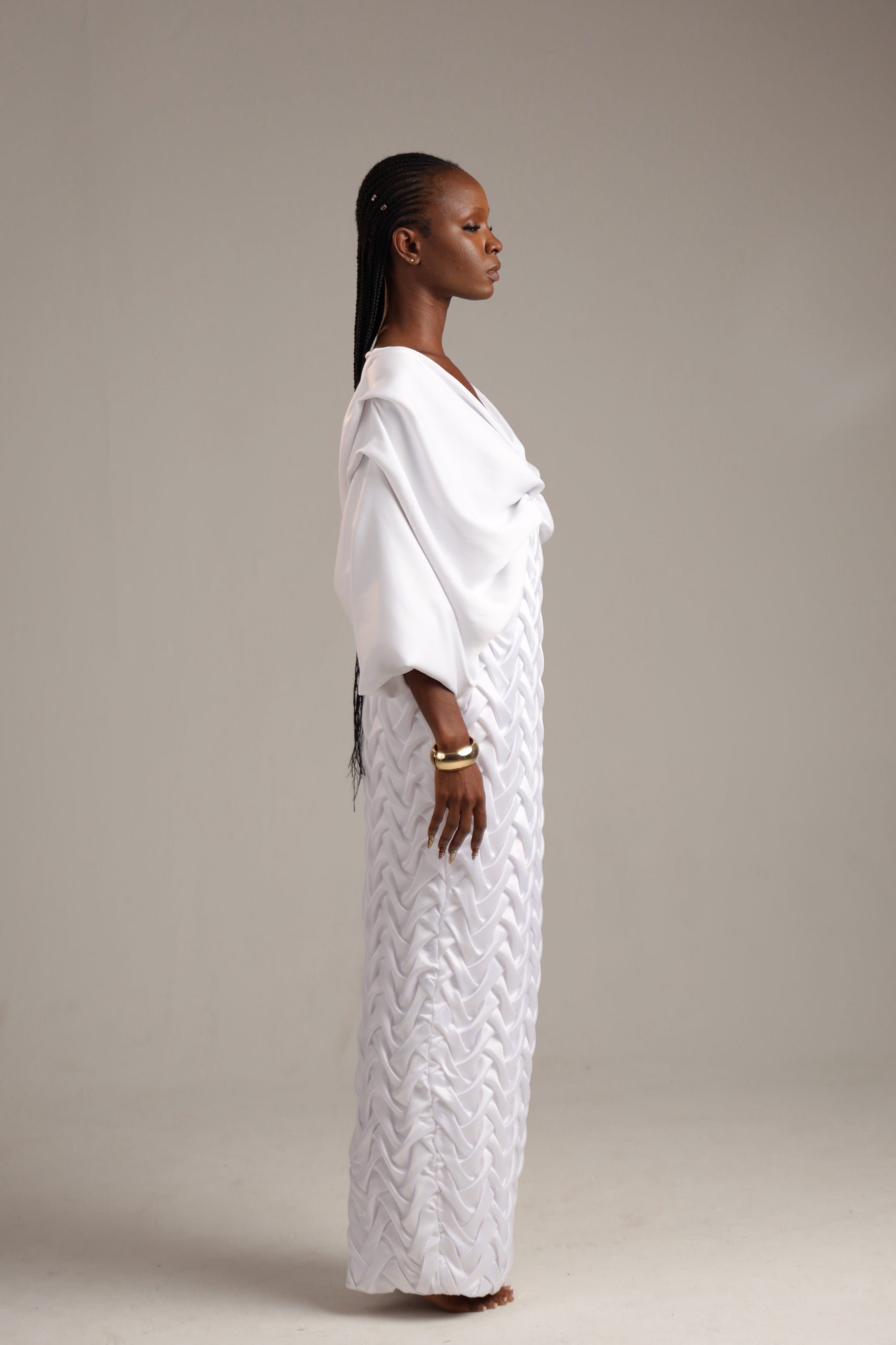 Woman wearing a white dress with a textured pattern on a plain background